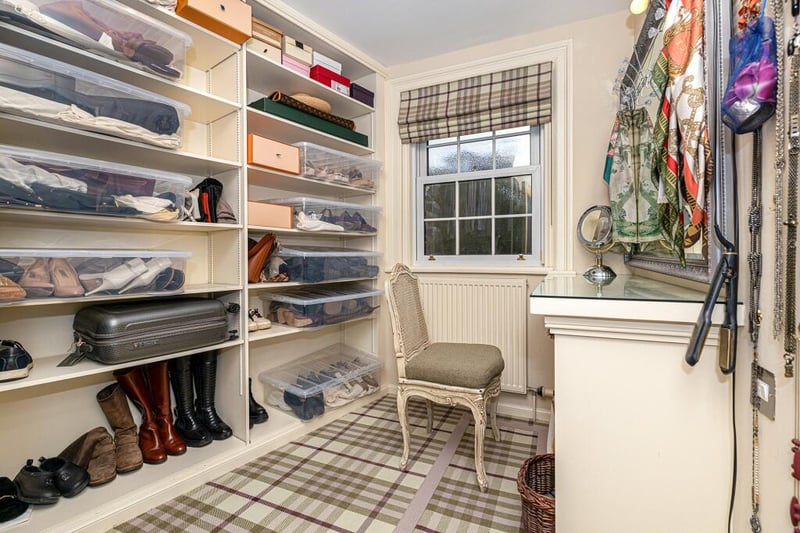 The dressing room space is fitted with shelves, hanging rails, and a dressing/make up table.