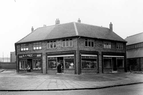 A parade of shops on Belle Isle Road, viewed from Moor Road. To the left can be seen R.H. Price, butcher. Pictured in March 1951.
