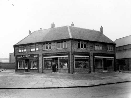A parade of shops on Belle Isle Road, viewed from Moor Road. To the left can be seen R.H. Price, butcher. Pictured in March 1951.