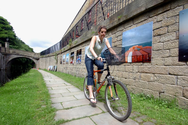 Photographer Casey Orr rides past her exhibition by Armley Mills after documenting her cycle ride from Armley along the Leeds Liverpool Canal to America on a container ship. Pictured in July 2007.