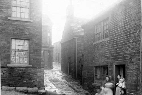 A back alley or ginnel off Town Street in May 1909.. A group of women and children stand in the doorway.