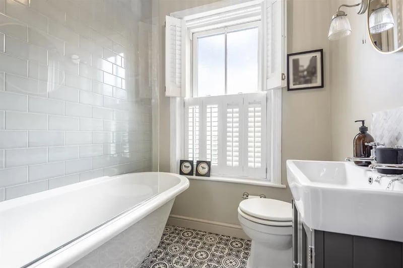 In the bathroom with beautiful flooring is a bathtub, with shower over.