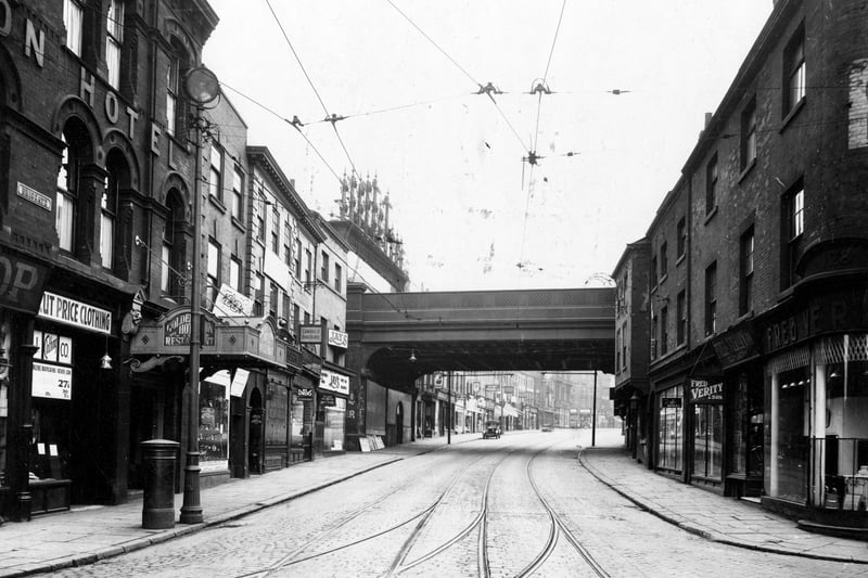 This view looks from the junction of Briggate with Call Lane, right, and Swinegate, left, through the London and North Eastern Railway bridge on Lower Briggate. The Golden Lion Hotel can be seen on the left with Fred Verity and Son, Ironmongers on the right. Pictured in June 1933.