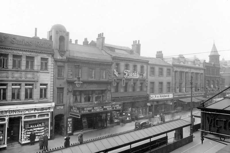 Briggtate in March 1938. Pictured, from left, can be seen Lyons and Co. Ltd; Bull and Bell yard; Rialto Cinema; Frank's Optician's; T.C.Palmer; Thornton's Ltd; and Mansfield and sons Ltd. Down the middle of the road can be seen bus/tram shelters. The Rialto opened in April 1911 at the Picture House, the 600-seat cinema was designed by Reginal Naylor and Sale. It had 'Wedgewood and Jacobean Tea Lounges', 'a beautifully designed tea room for the ladies, a smoke room for the men'. It became the Rialto in February 1927; this photograph was taken on 16 March 1938. It closed in March 1939, and was demolished to make way for the new Marks and Spencer store.