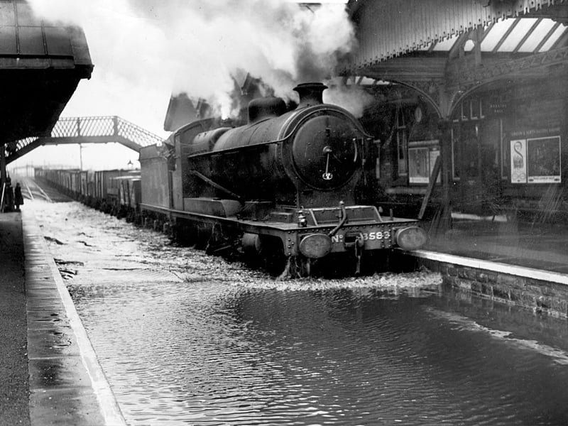 A steam train passes through a flooded Beighton railway station on February 3, 1950