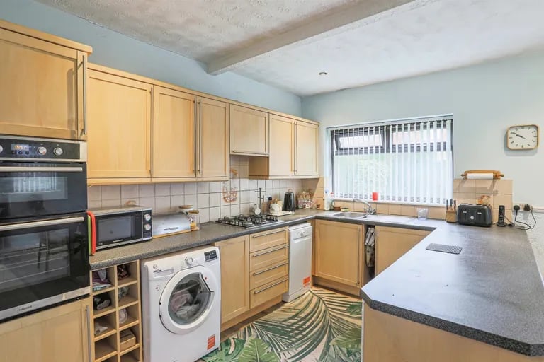 The fitted kitchen features a range of wall and base units with laminate work surfaces over.