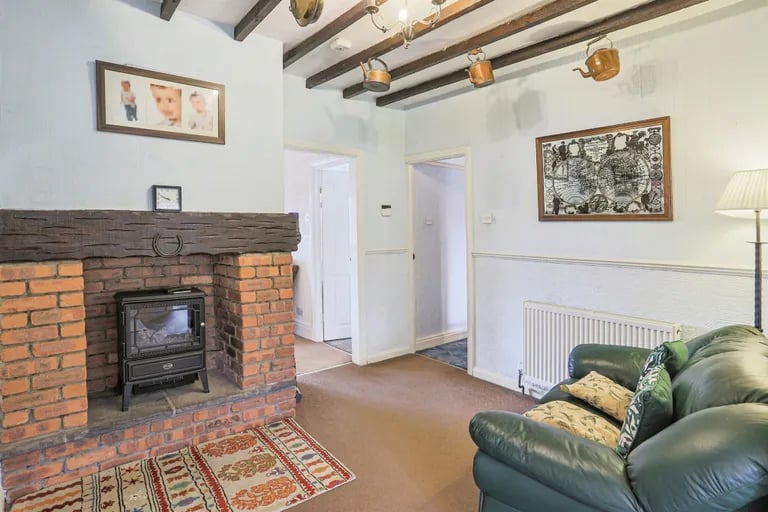 It has feature ceiling beams and exposed brick fireplace surround.
