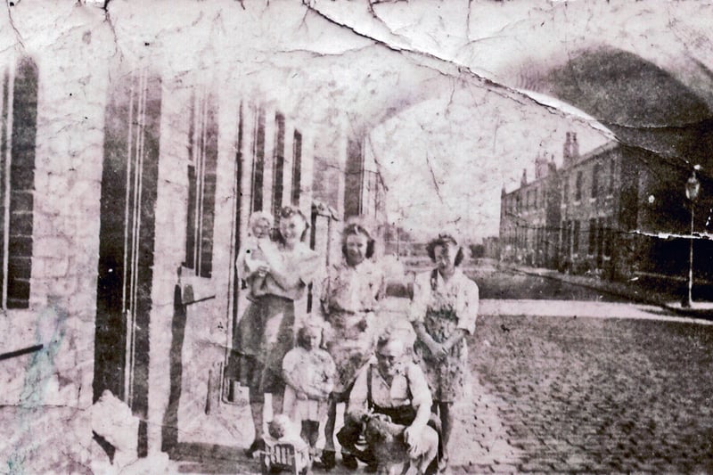 Barkston Terrace showing the Holbeck Viaduct. A family pose for the photograph outside no. 3, the centre house of a block of 3. Through the viaduct more terraced housing on Barkston Terrace can be seen, with nos. 7 - 19 on the left and 10 - 20 on the right. The view looks from the direction of Croydon Place and dates from the mid to late 1940s.