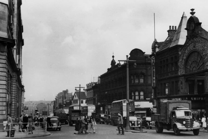 The Headrow, looking east towards Quarry Hill Flats, which can be seen in the distance. on the right can be seen Schofield's department store at number 79-83, the entrance to Victoria Arcade, Shiphams hosiers and Campbells house furnishers at number 75, Lands Lane, and Benefit Footwear at number 69.The edge of Lewis's department store can be seen on the left.