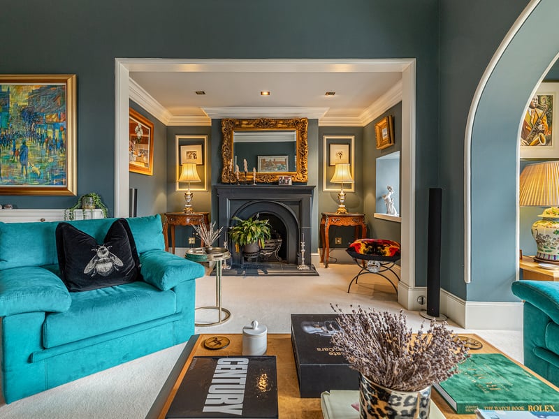 On one side is a sitting room with a large window, archway and classically designed reproduction fireplace with a gas fire.