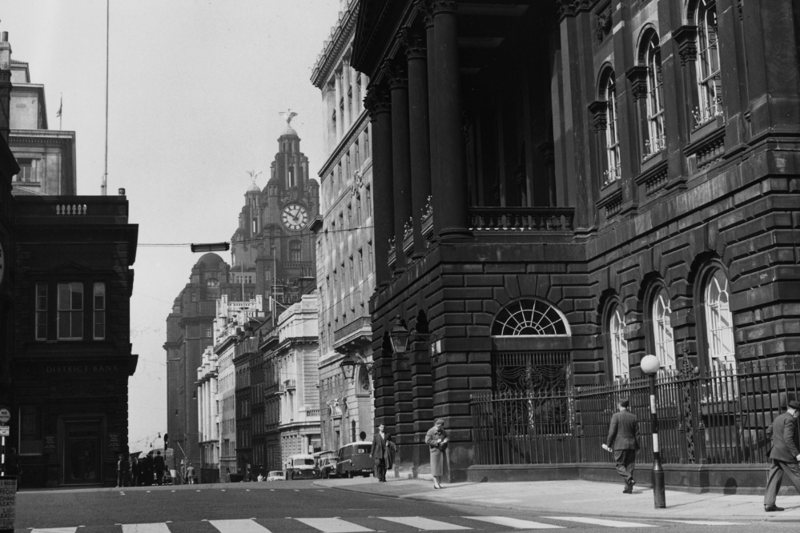 People walk around Liverpool town hall, with the Liver Building visible in the background in May 1963. 