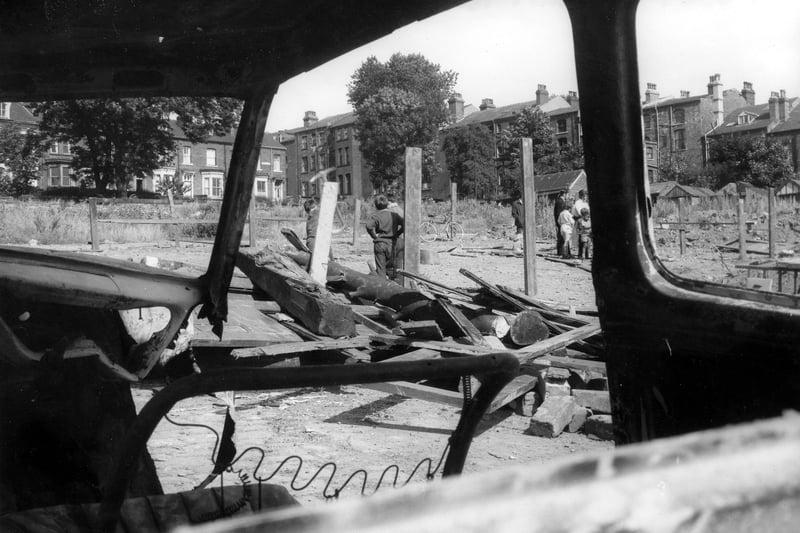 This view looks through an abandoned car across a temporary adventure playground located on land lying between Hyde Park Road and Woodsley Road. In the background are houses on St. John's Grove and St. John's Avenue. Pictured in August 1969.