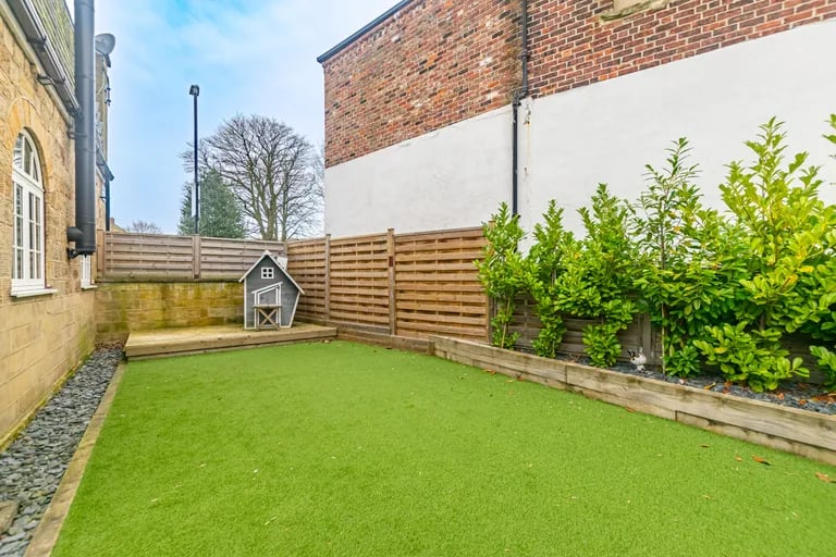 Here you will find an artificial lawn and raised decking along with planted borders.