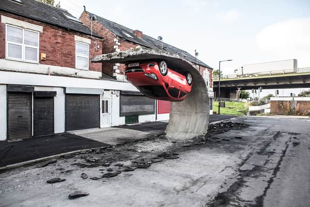 Sculpture of a car hanging upside down, creating the illusion that a section of road was peeling up from beneath it. The Tinsley artwork, which was installed in 2017, was visited by more than 5,000 people over five days, it is claimed