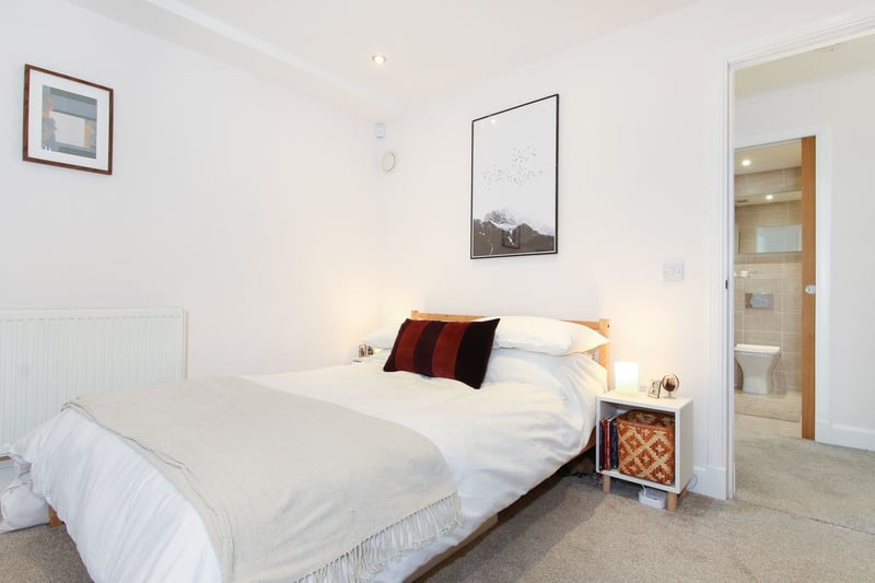 A carpeted stairway leads down to the accommodation on the lower level, comprising this generous double bedroom with built-in wardrobes, as well as additional walk-in storage and a handy utility room.