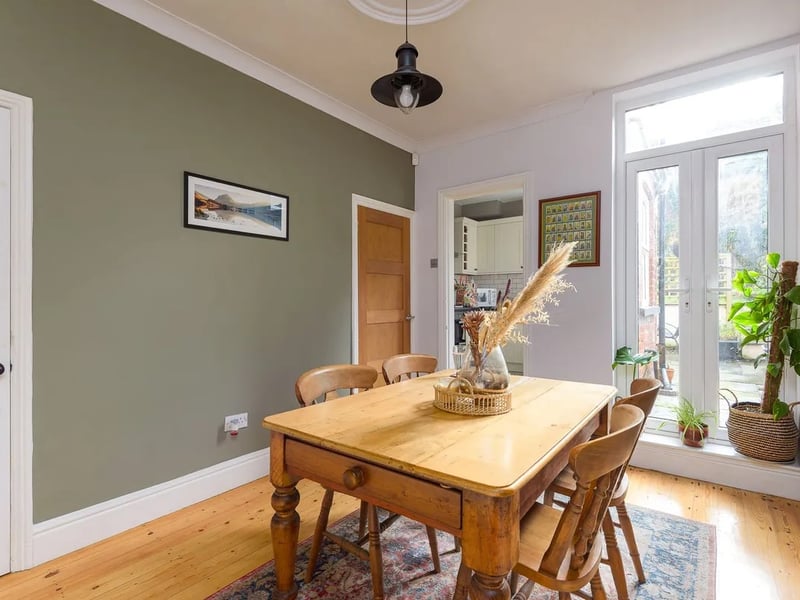 In order to reach the kitchen, you'll need to walk down the hall and then through this bright dining room.