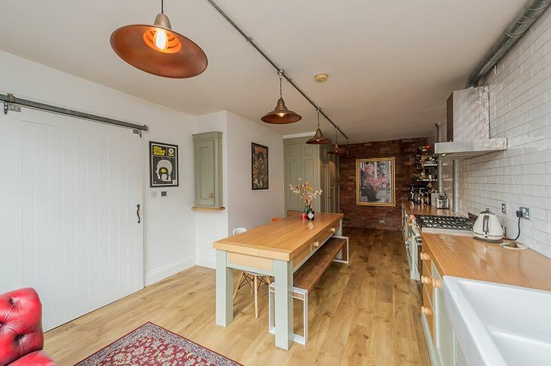 The room is accessed via a large wooden sliding door while the wall features exposed painted bricks.