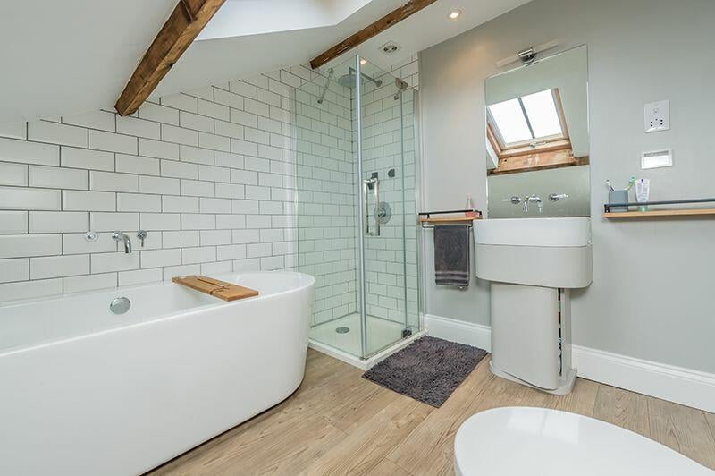 This stunning bathroom has a fully tiled shower cubicle with a chrome thermostatically controlled shower unit and a freestanding bathtub.