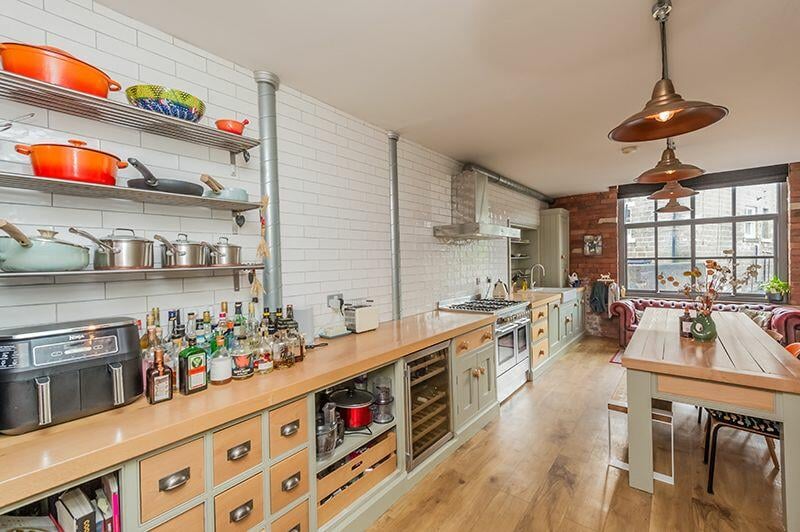 The impressive dining kitchen features a range of bespoke units with butcher wood worktops and brick effective tiling above.