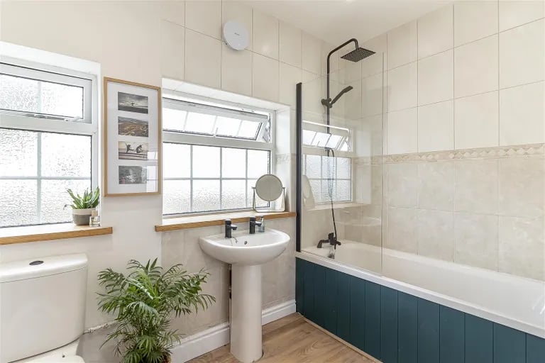 The luxurious family bathroom features a bath with rainfall shower over.