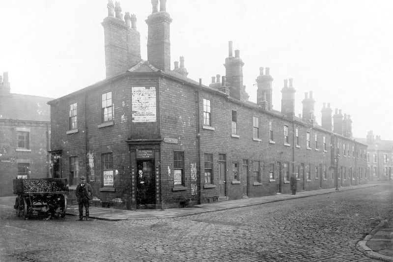 The junction of Clifton Street with Benson Street. Property on the corner is J.C. Shepard, The Clifton Toilet Saloon, which is number 16 Benson Street, the proprietor poses in the doorway. Outside just before junction with Pease Street a coal cart is parked with a man standing beside it. Pictured in October 1928.