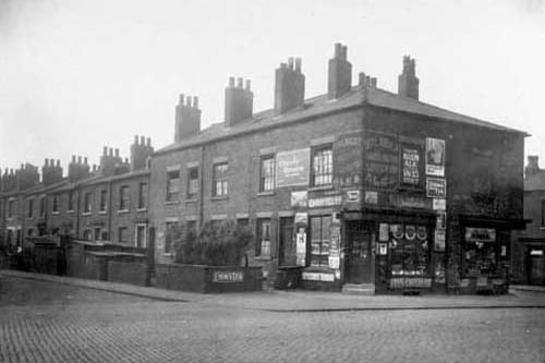 A view taken from Cross Stamford Street of St Lukes Street. Shop on left is number 9 Cross Stamford Street and is the business of Daniel Cohen, Shopkeeper with John William Pawson general store next door. Painted advertising signs can be seen. Junction with Stamford Street on the right. Pictured in June 1929.