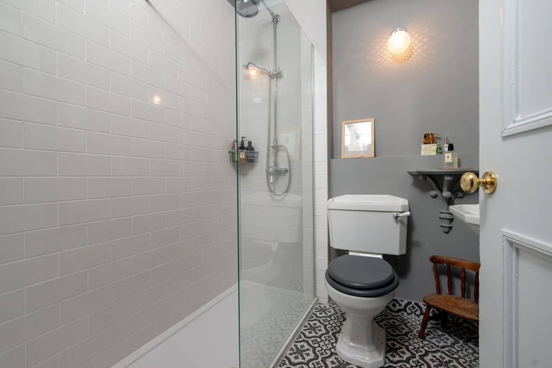 The modern shower room with white three-piece suite comprising shower unit with deluge head, WC and wash hand basin.
