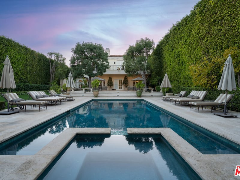 The far end of the backyard also houses both an incredibly large swimming pool but also a small bathing pool that provides a small water feature into the main pool. (Credit: The MLS)