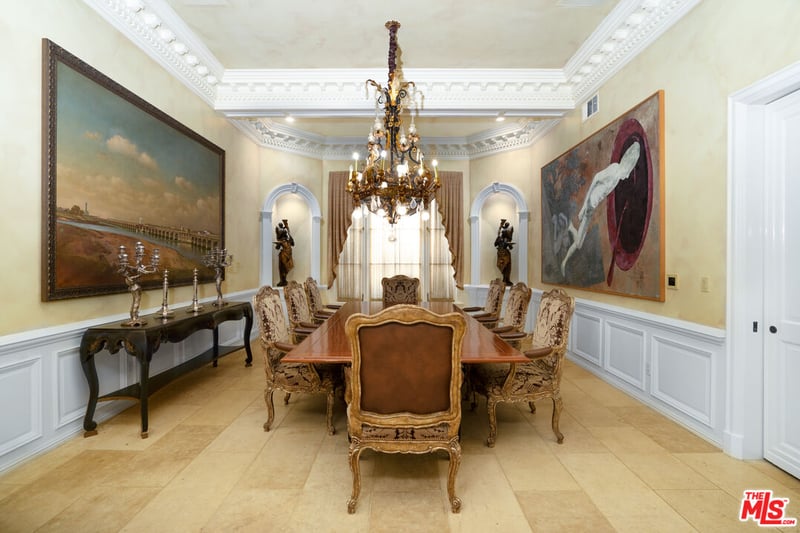 The grandiose dining room, complete with landscape art pieces, chandelier and wooden decor to set off the almost "renaissance" era aesthetic of this area (Credit: The MLS)