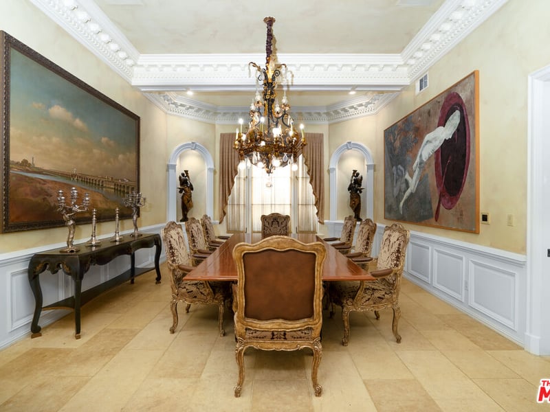 The grandiose dining room, complete with landscape art pieces, chandelier and wooden decor to set off the almost "renaissance" era aesthetic of this area (Credit: The MLS)