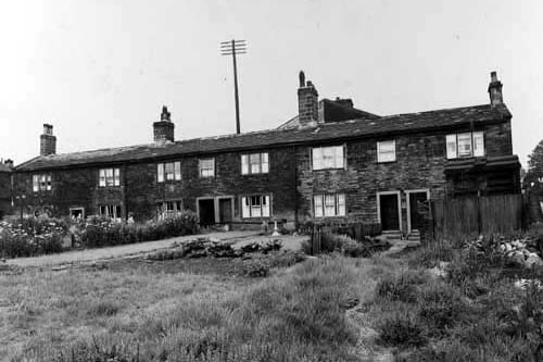 A row of stone cottages at the junction of Abbey Road and Kirkstall Lane in July 1938. Gardens in view, including a vegetable patch and a bird bath in one.