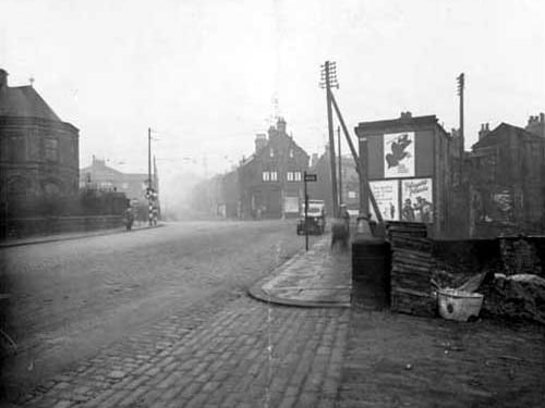 A view from Bridge Road toward junction with Abbey Road (Left 7, Kirkstall Lane) and Commercial Road to the right. The Police station is on the left in centre of photograph. Midland Bank can be seen on corner (this is number 1 Commercila Road, Manager Ernest Palmer). A Leeds City Transport bus stop is visible on the right. Pictured in January 1937.