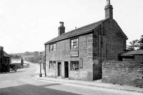 Looking across Morris Lane from the bottom of Kirkstall Hill, at the junction with Kirkstall Lane. Number 1 Kirkstall Hill is home of Allan Lye, forgeman. Number 3 is a boot and shoe repair shop, business of John Arthur Stammers. Pictured in May 1935.