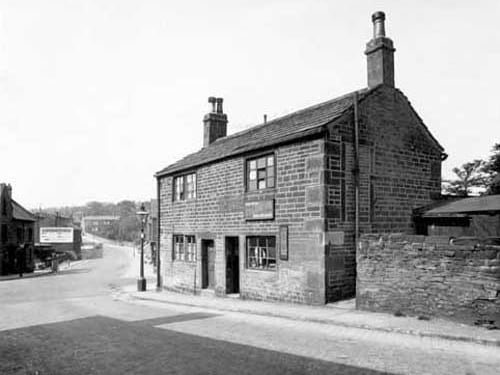 Looking across Morris Lane from the bottom of Kirkstall Hill, at the junction with Kirkstall Lane. Number 1 Kirkstall Hill is home of Allan Lye, forgeman. Number 3 is a boot and shoe repair shop, business of John Arthur Stammers. Pictured in May 1935.