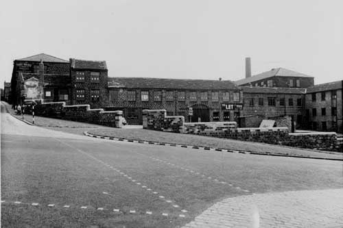 Improvements to wall and factory at junction of Kirkstall Hill. Tubex Silencer Co can be seen through gateway in stone wall. Thomas Waide and Sons, Printer to left of photo. Also in view is a belisha beacon and a woman and child pushing a pram. Pictured in July 1938.