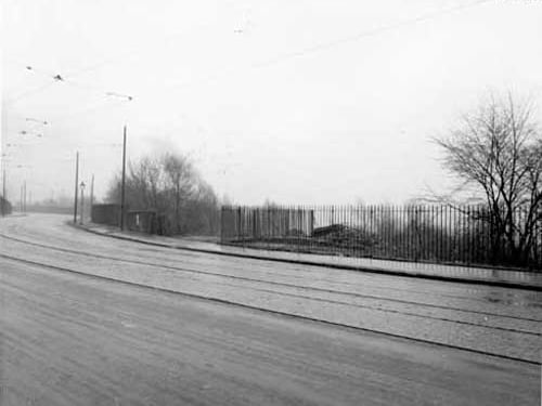 Abbey Road showing railings and new entrance at the northern end of Kirkstall Forge grounds. The forge is an historic site, metal being smelted since 1200AD by Cistercian Monks of Kirkstall Abbey. Passed through varied ownership, became renowed for manufacture of heavy axles. Due to be closed by present owners, ending 800 years of forging in this place. Tramlines can be seen in road, with overhead cabling system. Pictured in November 1937.