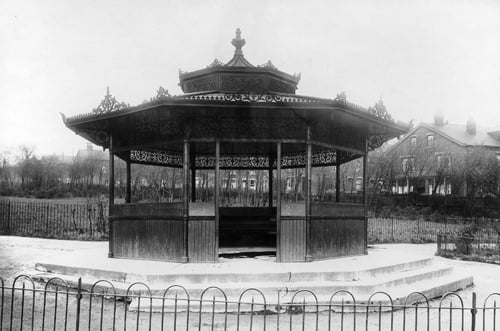An octagonal wooden shelter in Cross Flatts Park. The park, which covers 44 acres between Beeston Road and Dewsbury Road, opened in 1891. Houses can be seen in the background. Pictured in April 1923.