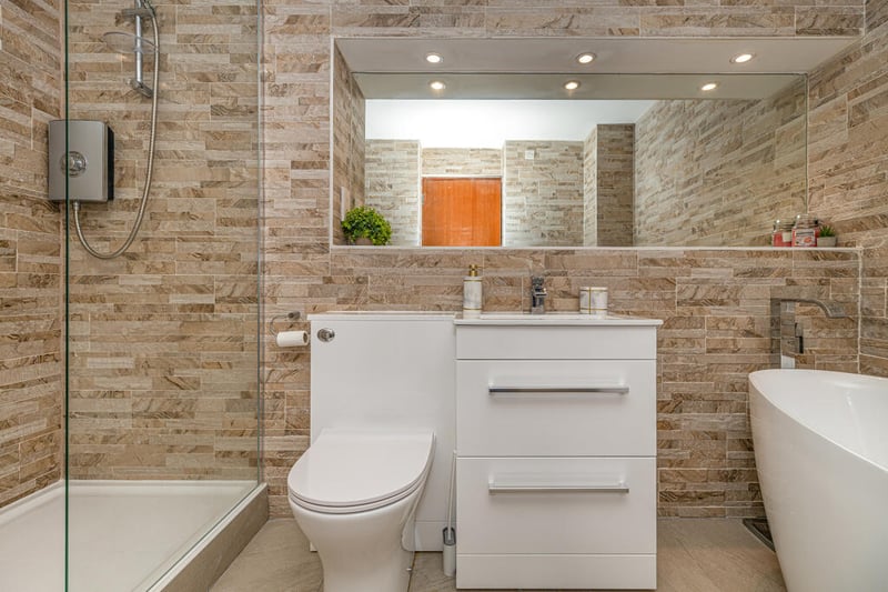 The refitted main four-piece bathroom has tiled floor and wall coverings, a freestanding bath and walk in double sized shower with glass screen. 