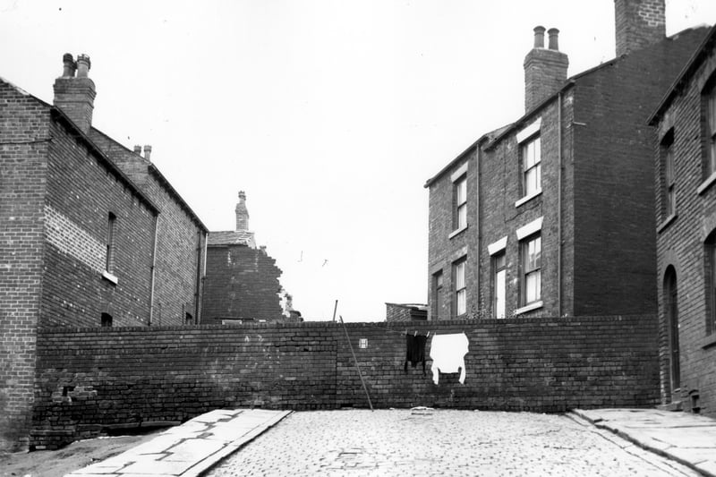 This view looks down Rillington Street across a wall onto the backs of numbers 20 and 22 Cayton Street, to the left, and numbers 17 and 15 Cottingham Street to the right. Number 12 Rillington Street can just be seen on the right edge. Included in the slum clearance plans. Pictured in February 1964.
