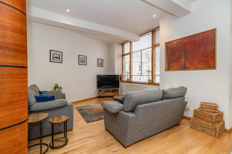 The open plan living space features real wood flooring and open aspects over Wilson Street. 