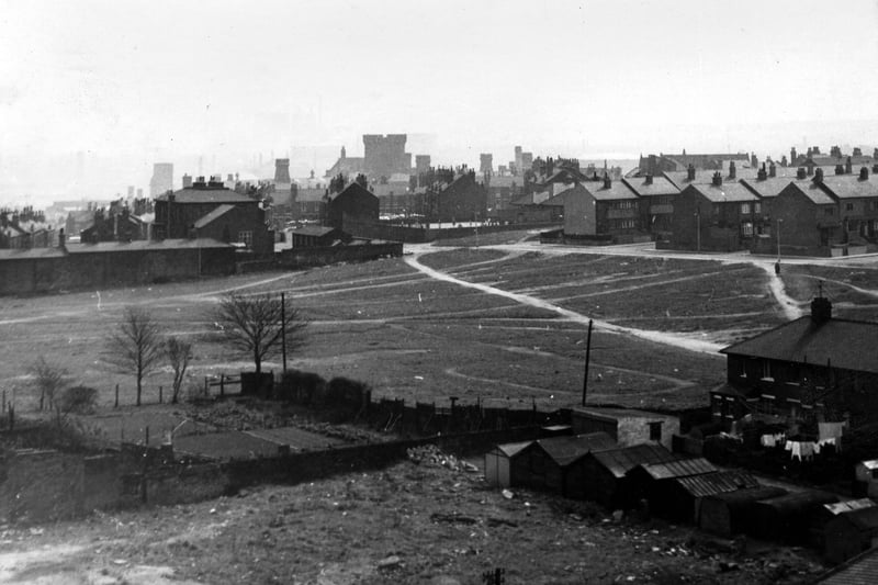 A photo taken from either Westerly Croft or Westerly Rise, blocks of flats that had recently been built by the junction of Armley Road and Stanningley Road. This view, from April1964 looks east across waste/recreation ground to houses at the top of Parliament Road, with beyond them the Abbotts and the Winchesters and in the background centre, Armley Gaol. In the background right are Model Avenue and Model Road and behind them Holy Family R.C. School, while in the foreground on the far right is the end of a block of houses on Nancroft