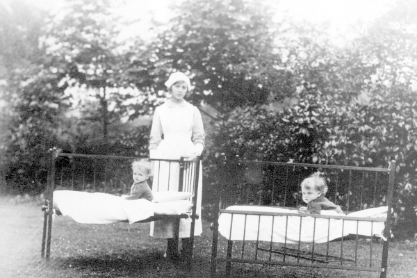 A nurse poses with some babies on outdoor pallet beds at the Scotstoun Day Nursery