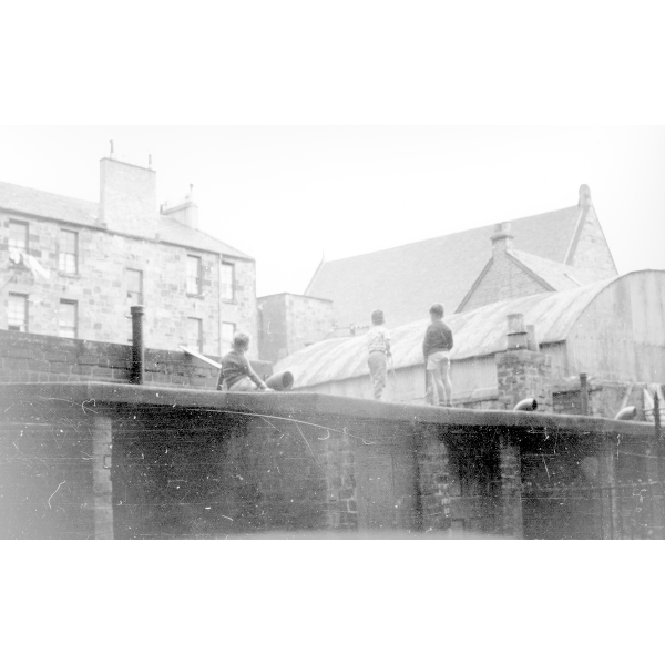 Children climb up on some old sheds in a back-court in Partick