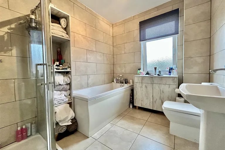 The large tiled bathroom with a four-piece suite featuring separate shower cubicle and panelled bath. 