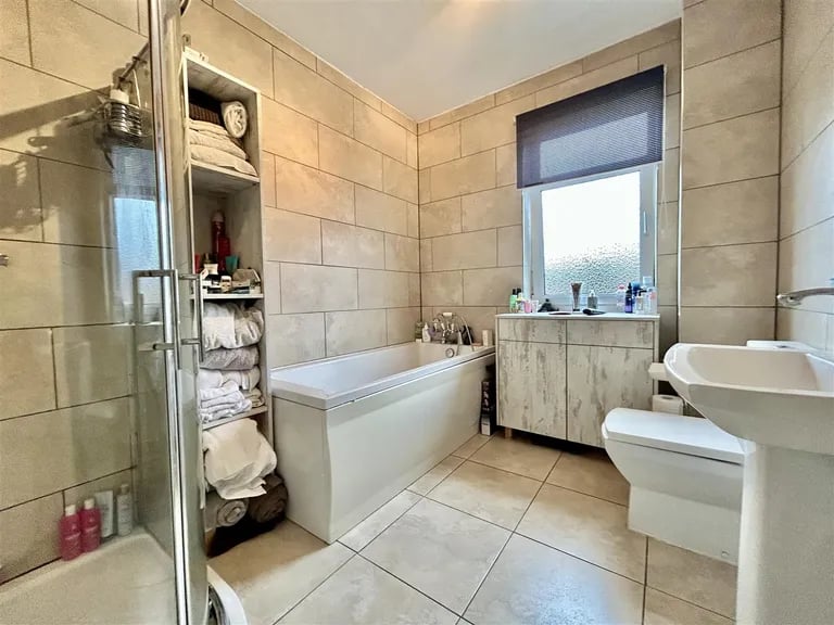 The large tiled bathroom with a four-piece suite featuring separate shower cubicle and panelled bath. 