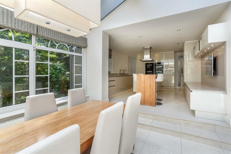 The home has a bespoke fully fitted kitchen with integrated appliances and steps leading to an informal dining room.