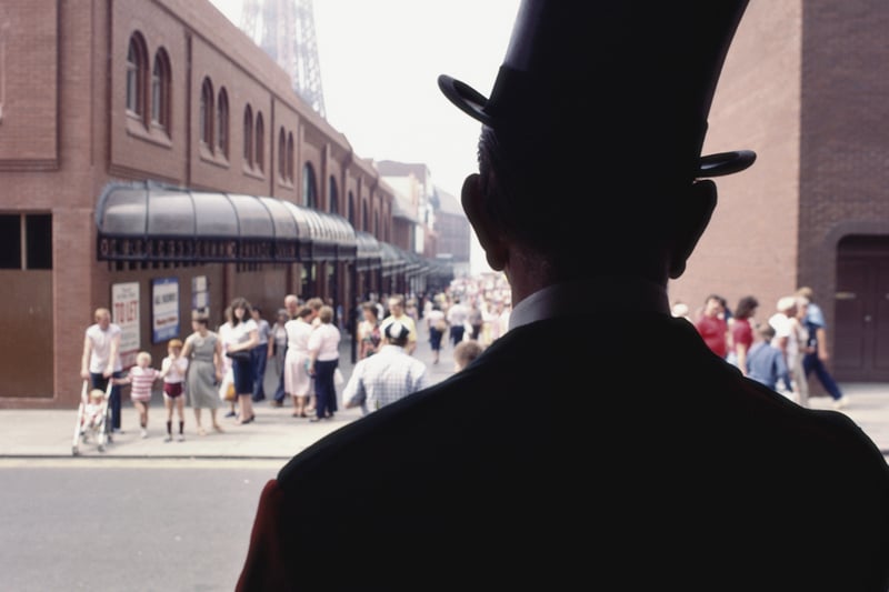 A doorman in a top hat looks out from the entrance of the Winter Gardens theatre in the seaside town of Blackpool, Lancashire, August 1983