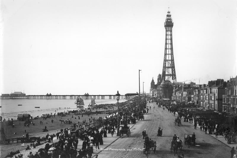 The Promenade, 1894-1910. A busy street view looking north along Blackpool promenade towards Blackpool Tower. The tower was built in 1891-1894 by Maxwell and Tuke. A few sailing boats can be seen taking holidaymakers on rides from the shore
