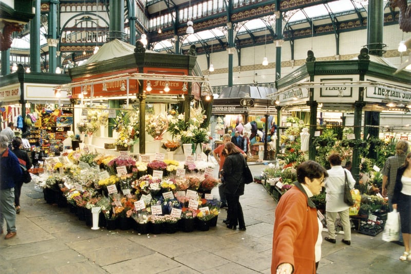 shoppers and stalls inside Kirkgate Market. Flower stalls are prominent to the left and right of the photo from  September 1999.