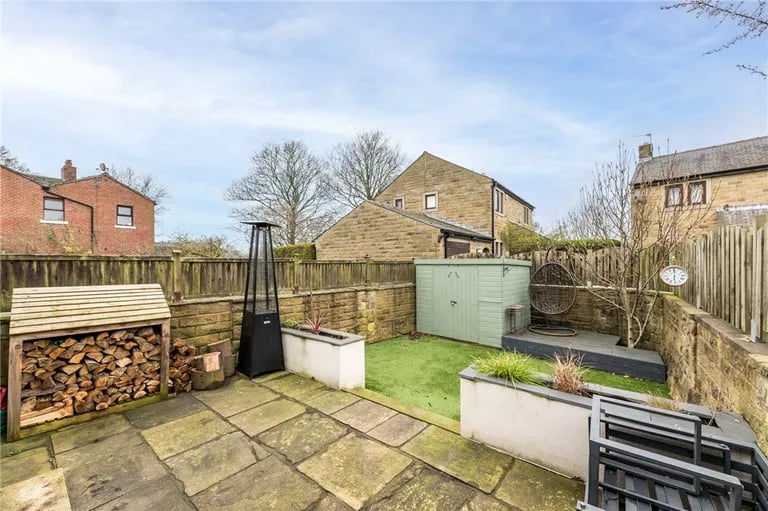 This enclosed space features a Yorkshire stone patio, artificial lawn, garden shed and raised decked area.
